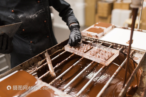 生产,烹饪人的糖果糖果店的霉菌中除多余的巧克力糖果模子里取出多余的巧克力